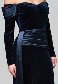 Samtiges schulterfreies Kleid in tiefem Marineblau, mit tailliertem Oberteil, langen Ärmeln und einem breiten Satinschärpen, der in der Taille gebunden ist.