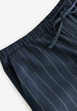 Marine gestreifte Stoff-Jogger mit einem elastischen Bund und Kordelzug. Merkmale sind vertikale weiße Streifen und eine glatte Textur.