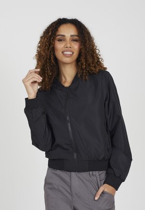 Giacca bomber nera realizzata in tessuto liscio, con zip frontale, polsini a coste e vita aderente. Il design è casual e leggero.