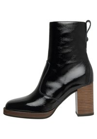 Bottine noire à talon haut en cuir verni, à bout carré, avec un talon en bois et une languette à l'arrière. Texture lisse partout.