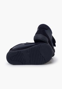 Námořnické modré obuvi vyrobené z nubuku a gumy, se zapínáním na suchý zip. Podešev má texturované drážky pro lepší přilnavost a stabilitu.