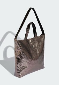 Metaliczna, fioletowa torba typu tote o fakturowanym wykończeniu, wyposażona w dwa uchwyty i dyskretne logo z przodu. Prosty, kanciasty kształt.