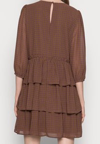 Braunes, gestuftes Kleid mit Puffärmeln, das ein Karomuster in Lila und Gelb aufweist, einen Schlitz im Rücken sowie einen elastischen Bund für optimalen Sitz.