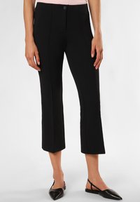 Zwarte cropped broeken met een gestructureerd oppervlak, aansluitende pasvorm en voornaaddetails, gecombineerd met zwarte slingback schoenen.