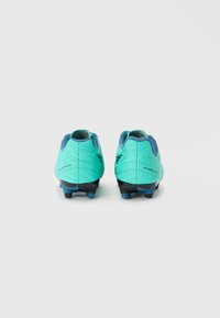 Un paio di scarpini da calcio teal e blu visti da dietro, con suole chiodate e la parola "Evolution" su ciascun tallone.