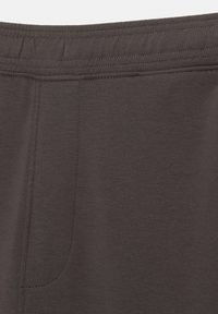 Bruine elastische tailleband met subtiele stikdetails; gladde stofstructuur; voorzien van een zijzak; minimalistisch ontwerp.