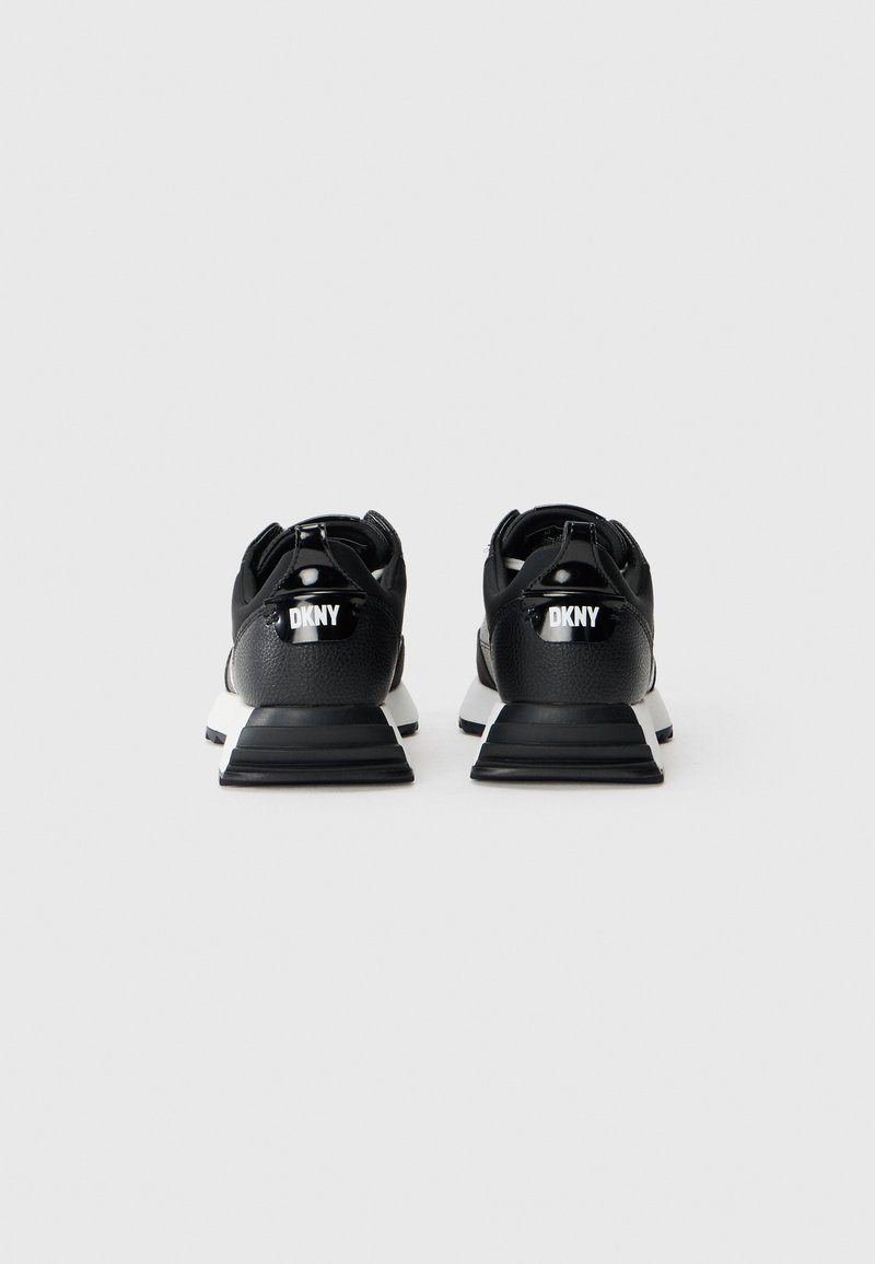 Baskets de sport noires au design épuré, avec un dessus texturé, des accents blancs et un logo DKNY bien visible à l'arrière. Semelle rembourrée et épaisse.