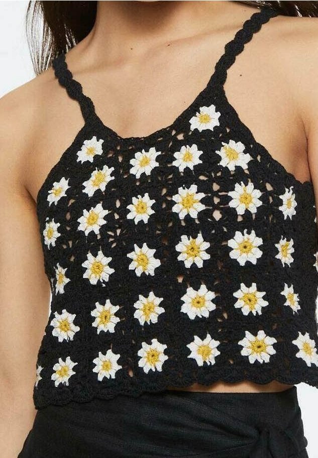Top court en crochet noir orné de motifs floraux blancs et jaunes, avec des bretelles fines et un ourlet festonné. Tissu doux et texturé.