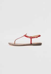 Red leather flat sandals with a T-strap design, adjustable ankle strap, and textured brown insole, featuring minimalistic stitching details.