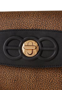Borsa a tracolla in pelle marrone con una fascia nera, caratterizzata da una chiusura circolare dorata con il nome del marchio "Borbonese."