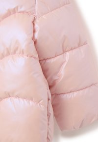 Giacca a vento rosa chiaro con un esterno lucido e imbottito. Presenta grandi sezioni con cuciture in rilievo e una superficie liscia.