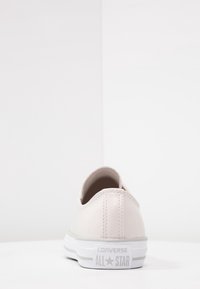 Ljusrosa läder lågtopp sneakers med rundad baksida, vit gummisul och grå "Converse All Star"-logotyp på hälen.