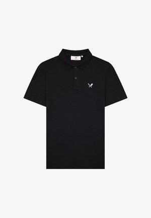 Camiseta polo negra de manga corta con tapeta de dos botones y pequeño logo blanco de cuchillo cruzado y espátula en el pecho izquierdo.