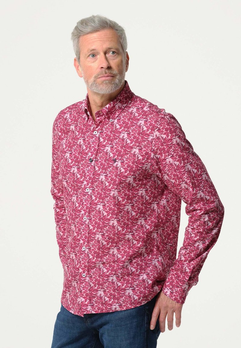 Lange mouw blouse in het roze met een wit bladerenpatroon. De stof is glad met een ontspannen pasvorm. Heeft een klassieke kraag en knopen.