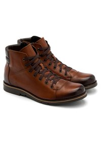 Brązowe skórzane buty typu mid-top z teksturowaną powierzchnią, zaokrąglonym noskiem, ciemnymi sznurówkami i kontrastującym akcentem na obcasie.