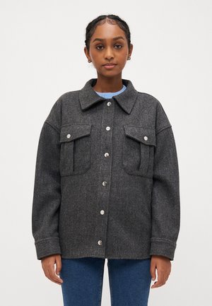 Grå ullblandad jacka med knappuppknäppning framtill, två bröstfickor och klassisk krage. Har en avslappnad passform och mjuk textur.