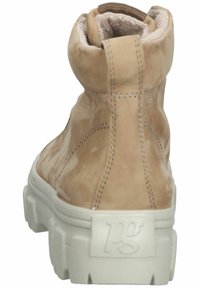 Stivale alto in suede color beige con suola lug bianca spessa e il logo "pg" stampato sulla linguetta del tallone, presenta cuciture a vista e una fodera imbottita nella zona del collo.