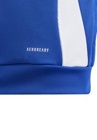 Blå atletisk topp med teksturert stoff, hvite sideakenter og "AEROREADY"-merke i hvitt på den nedre delen.