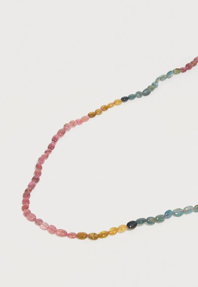 Perles ovales de couleurs arc-en-ciel enfilées en collier, disposées en dégradé de rose, jaune, vert et bleu sur fond blanc.