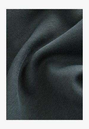 Tume roheline tekstureeritud kangas, millel on sile, kudumise muster. Materjal näeb välja pehme ja veidi veniv, näidates voldid ja langused.