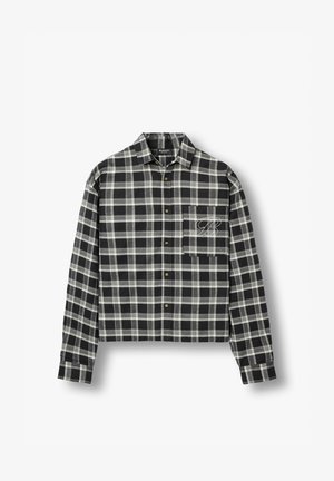 Chemise à manches longues à carreaux noirs et gris, à boutons, avec col et poche poitrine brodée d'un "B" cursif sur fond blanc.