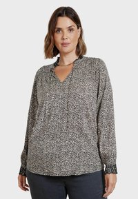 Blusa a fantasia bianco e nero con scollatura a V, caratterizzata da pieghe e polsini elasticizzati con rifinitura in pizzo. Realizzata in un tessuto leggero.