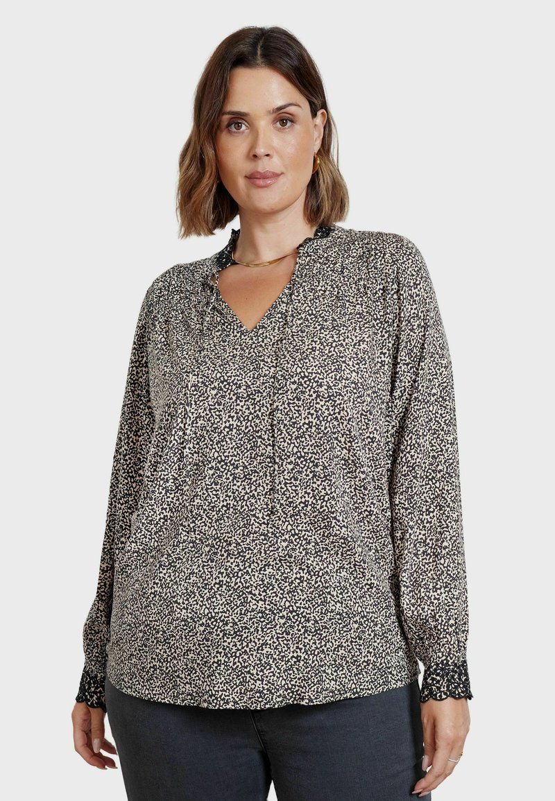 Blusa a fantasia bianco e nero con scollatura a V, caratterizzata da pieghe e polsini elasticizzati con rifinitura in pizzo. Realizzata in un tessuto leggero.