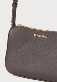Dark gray leather handbag with a textured finish, gold hardware, and logo. Features a zip closure and a shoulder strap. Compact design.