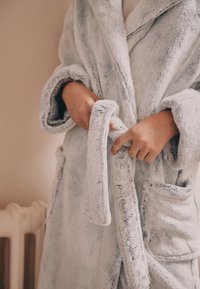 Accappatoio azzurro chiaro in morbido tessuto, con collo sciallato, cintura in vita, due tasche ai lati e una trama soffice e piacevole al tatto.