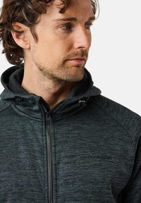 Dark grey zip-up hoodie featuring a textured fabric, adjustable hood, and black logo on the chest. Side panels in a contrasting shade.