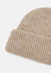 Bonnet en tricot beige avec un motif à côtes texturées et un revers plié, fabriqué en mélange de laine douce.
