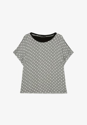 Blusa a maniche corte bianca e nera con righe verticali e piccolo motivo ovale bianco, scollatura rotonda con bordo nero solido.