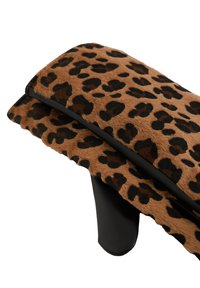 Cuscino in pelliccia sintetica con stampa leopardata, base in pelle nera, forma rettangolare e superficie testurizzata. Dettagli includono un tessuto morbido e stampato.