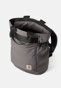 Sac fourre-tout en nylon gris avec double anse, une bandoulière réglable et une ouverture à fermeture éclair sur le dessus ; présente un petit patch logo.