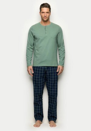 Haut à manches longues en coton vert clair avec une poche poitrine et trois boutons. Pantalon à carreaux bleu marine avec des accents verts et une ceinture élastique.