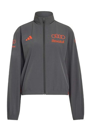 Ciemnoszara kurtka na zamek z wysokim kołnierzem, pomarańczowe logo Adidas po lewej stronie klatki piersiowej, pomarańczowe logo Audi i Revolut na klatce piersiowej i rękawach.