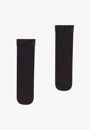 Calze nere con una cintura nera lucida decorata con strass, texture liscia e design al ginocchio. Realizzate in tessuto elasticizzato per il massimo comfort.