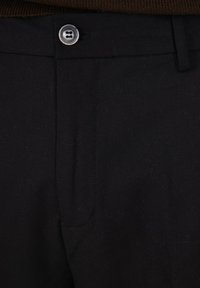 Pantaloni neri in tessuto intrecciato, dotati di chiusura con bottone e design frontale piatto. Texture liscia con una leggera lucentezza.