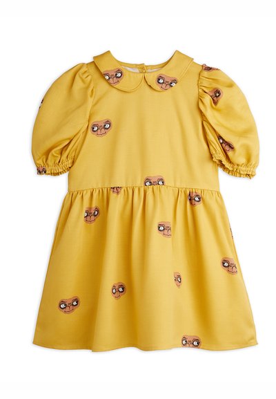 Kollane kleit paisutatud varrukatega ja ümmarguse kaelusega, millel on korduv graafik, kus on kujutatud koomiksite silmi ja nägusid. Pehme kangas sujuva tekstuuriga.