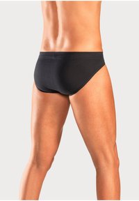 Slip da uomo neri con cintura elastica, realizzati in un tessuto morbido. Il taglio è a vita bassa, con una vestibilità aderente attorno alle gambe e alla schiena.