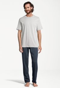 T-shirt en coton gris associé à un pantalon de détente à rayures bleu marine. Le pantalon possède une taille élastique et une coupe décontractée.