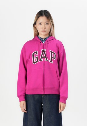 Magenta zip-up hettegenser med "GAP"-logo i hvitt, med en frontlomme og justerbar hette, brukt over en blå rutete skjorte.