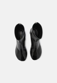 Černé kožené kotníkové boty s hladkým, lesklým povrchem, s rozepínáním na zip na zadní straně a těsným střihem.