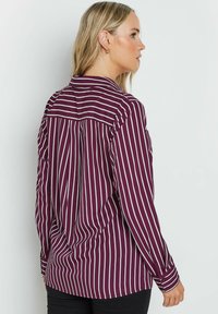 Bordeaux gestreepte vrouwelijke blouse met lange mouwen, knoopmanchetten en een achterpand ontwerp, met witte verticale strepen en een ontspannen pasvorm.