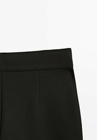 Czarne spodnie z płaskim paskiem w talii. Posiadają gładką fakturę i subtelne plisy z przodu. Prosty i elegancki design.