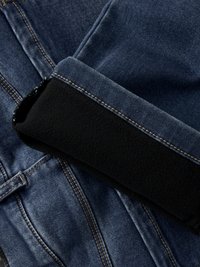 Jeans in denim blu scuro con cuciture dorate a contrasto, piegati con un morbido polsino in pile nero. Tessuto liscio con dettagli funzionali.