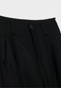 Black tailored pants with a smooth texture, featuring a button closure and pleated design. Focus on neat stitching and structured waistband.
