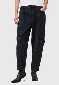 I pantaloni cargo in denim nero presentano una vestibilità comoda, tasche laterali, dettagli con cuciture curve e una chiusura con bottone in vita.