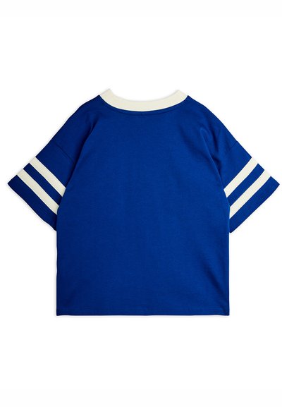 Μπλε κοντομάνικο πουκάμισο με λευκό ριμπ κολάρο και δύο λευκές ρίγες σε κάθε μανίκι, εμφανιζόμενο από πίσω.