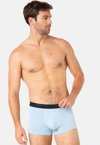 Boxers pour hommes bleu clair avec une ceinture élastique noire. Le tissu semble doux et lisse, épousant bien la taille et les cuisses.